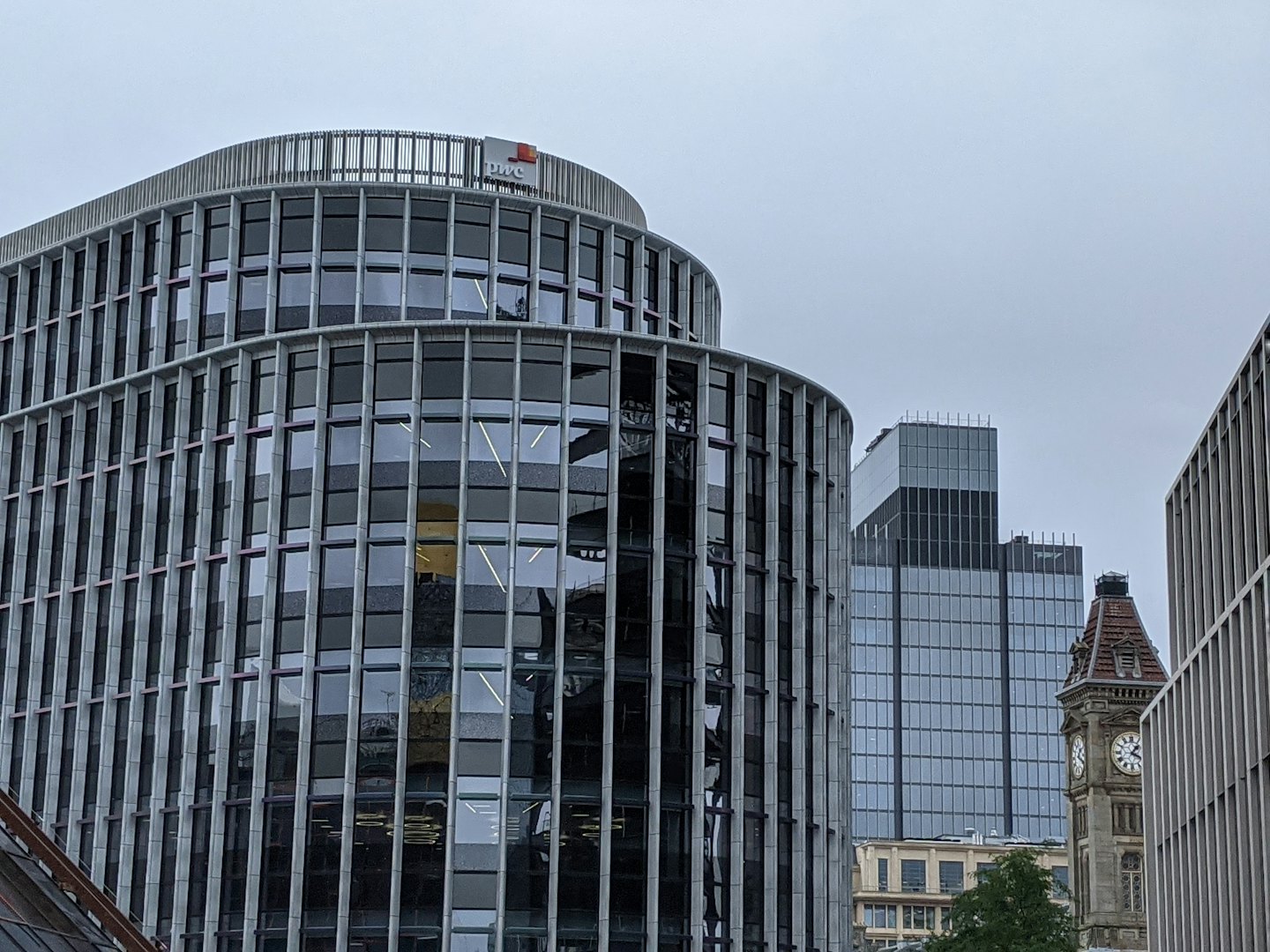 Moderni edifici in vetro e una torre dell'orologio in mattoni in città.