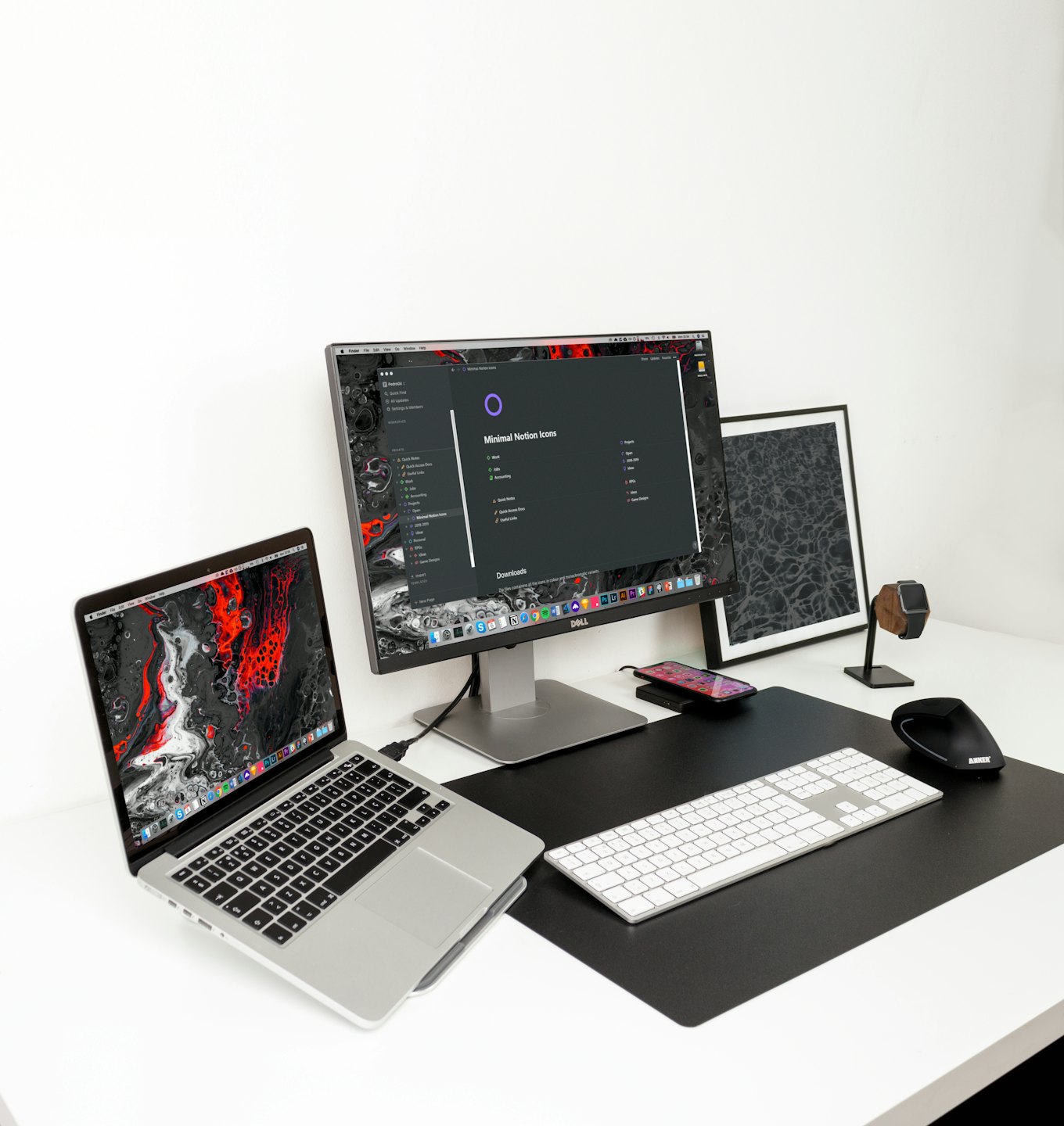 Spazio di lavoro minimalista con laptop, monitor e accessori da scrivania su una scrivania bianca.