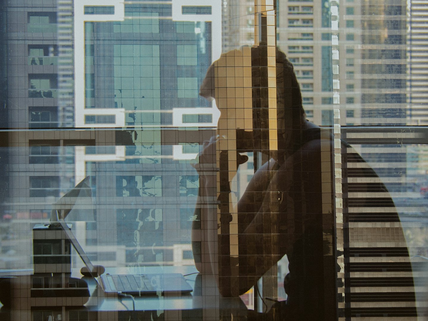 Professionista al lavoro su un laptop con vista sullo skyline di una città moderna.